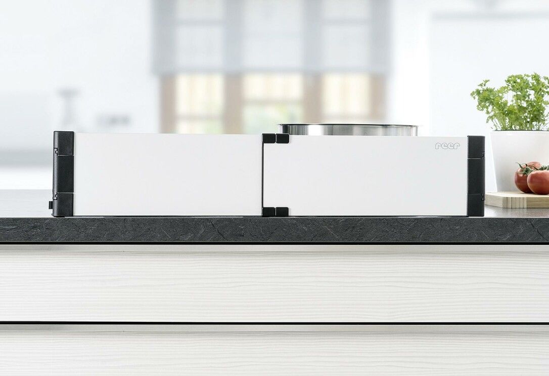 Protezione piano cottura Basic, bianca con angoli neri. Posizionata su un piano di lavoro.