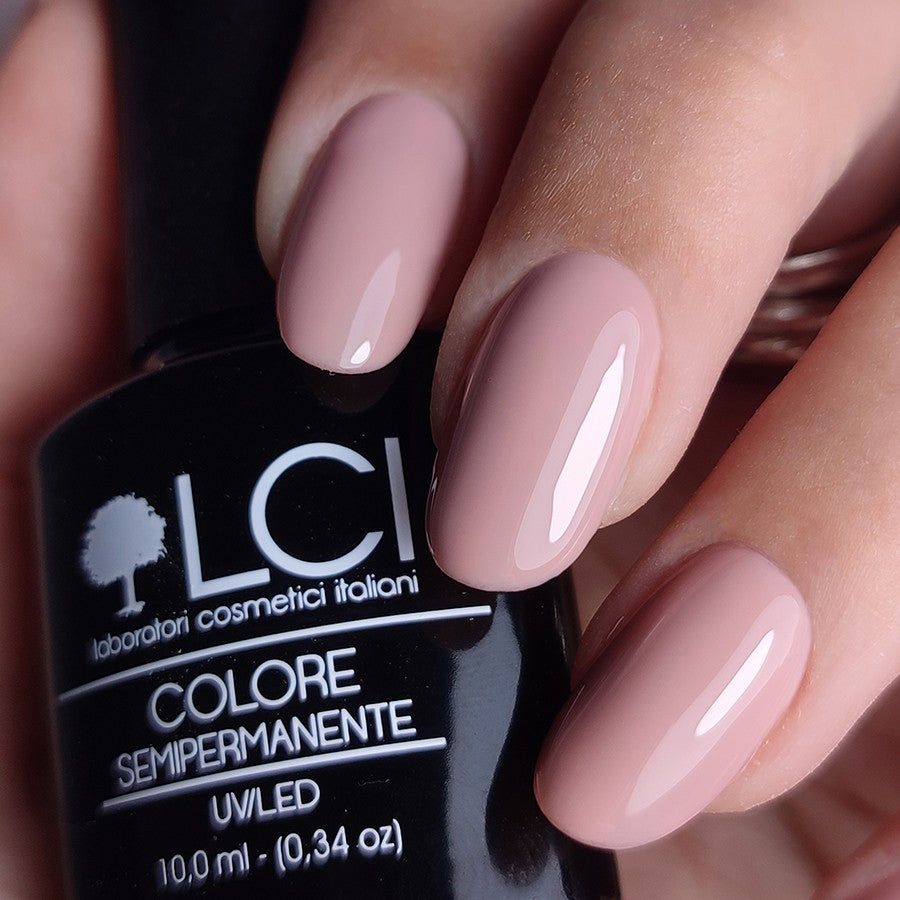 Mano con unghie smaltate di rosa. Flacone con scritta: LCI, Colore Semipermanente, UVLED.