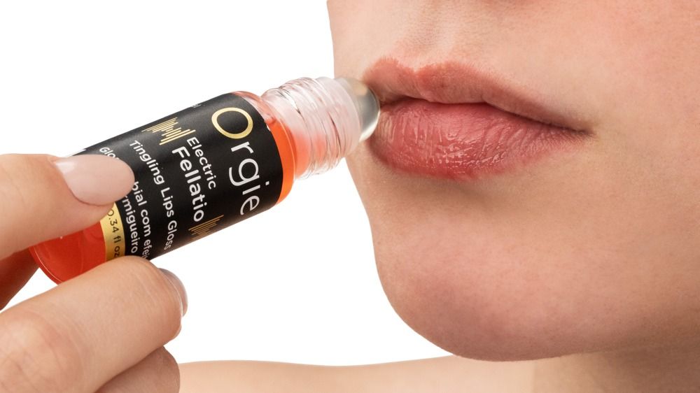 Applicazione di Orgie Electric Fellatio Tingle Lips Gloss sulle labbra.