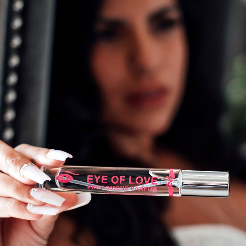 Flacone di profumo tenuto in mano. Scritta: EYE OF LOVE PHEROMONE PARFUM. Flacone con vaporizzatore. Donna con unghie lunghe.