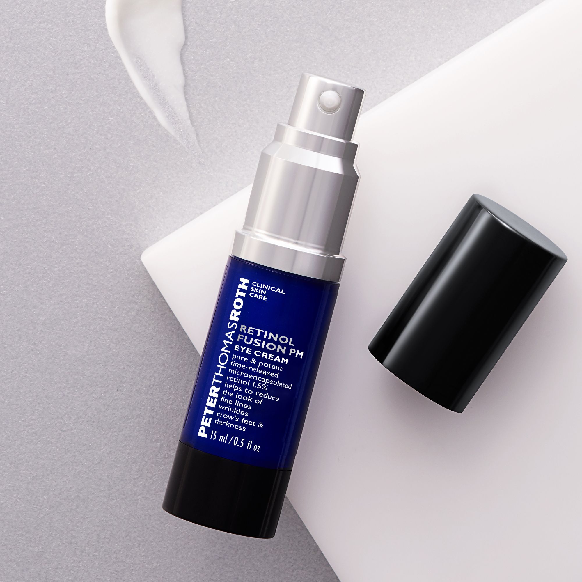 Flacone blu e argento con tappo nero. Scritta: Retinol Fusion PM Eye Cream. Capacità: 15 ml/0,5 fl oz. Tappo accanto.