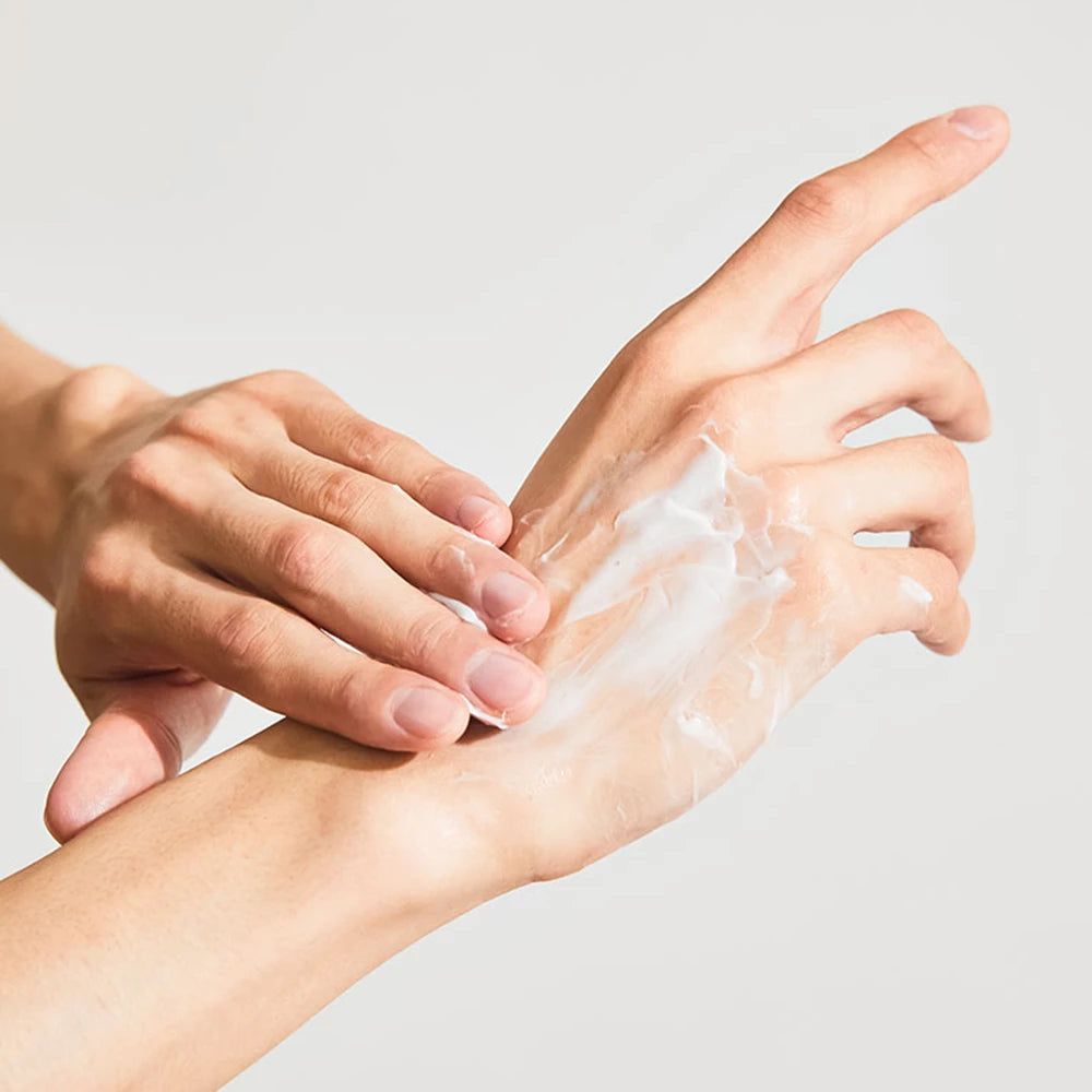 Mani che applicano crema sul palmo. Crema visibile. Pelle chiara.