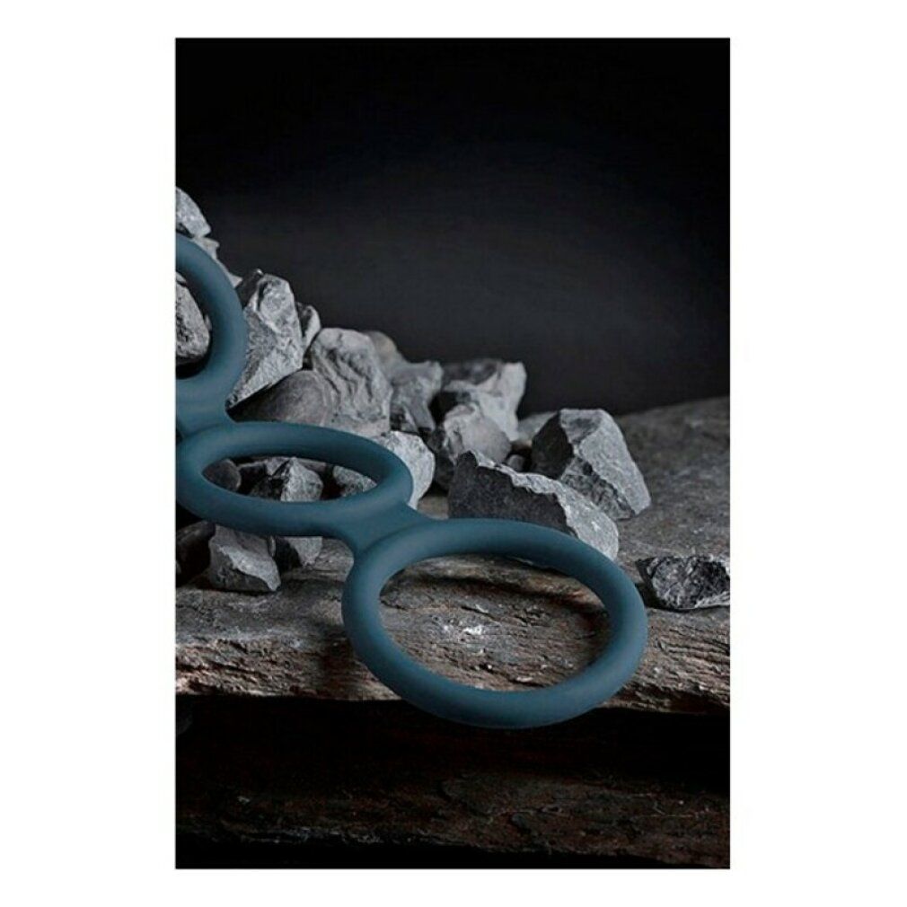 Anello per il pene blu a tre anelli. Posizionato su un fondo di pietre.