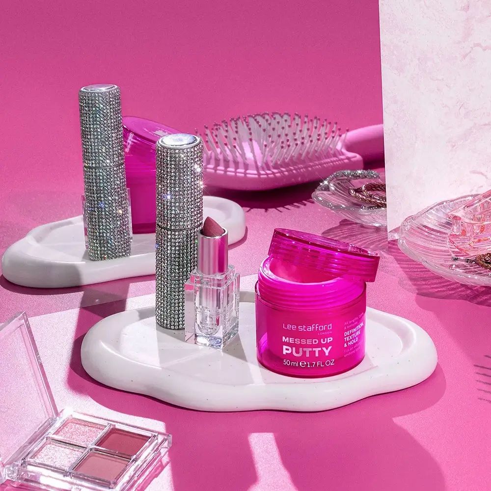 Vasetto di crema per capelli rosa aperto. Prodotti per il trucco e spazzola per capelli. Su vassoi bianchi.