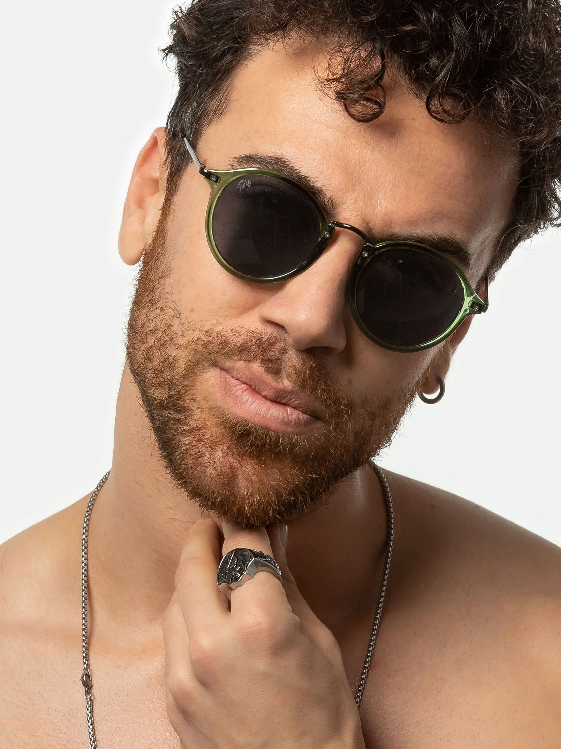 Uomo con occhiali da sole verdi. Lenti rotonde, aste nere. Marchio Twig.