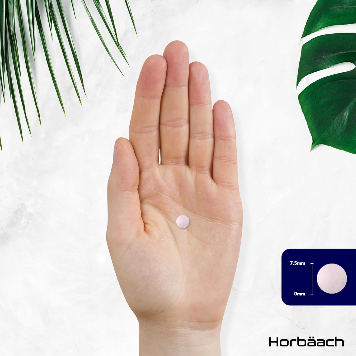 Mano che tiene una singola compressa, rotonda e rosa. Dimensioni: 7,5 mm x 6 mm.