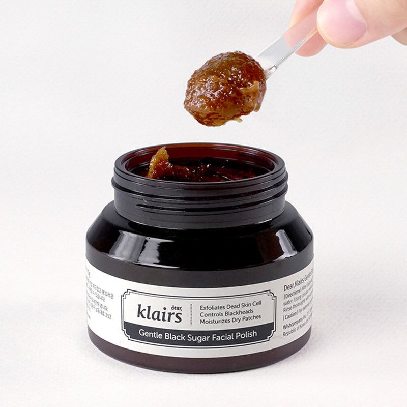 Pasta esfoliante allo zucchero marrone in un barattolo. Un cucchiaio ne contiene una porzione. Scritta: Dear Klairs Gentle Black Sugar Facial Polish.