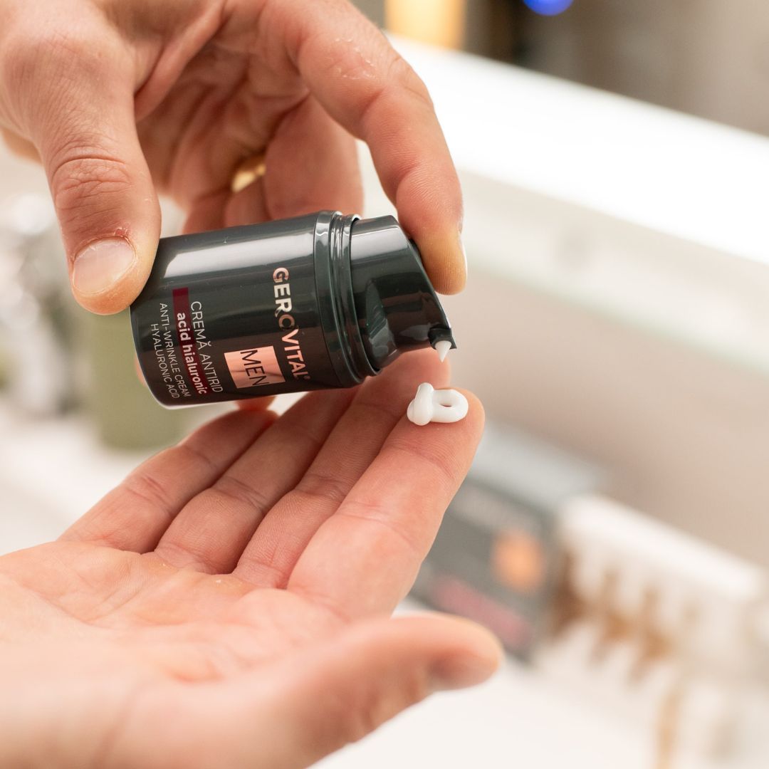 Mani che tengono un flacone di crema verde scuro. La crema viene erogata. Scritta: Gerovital MEN, Crema Antirid, Acid Hialuronic, Anti-Wrinkle Cream.