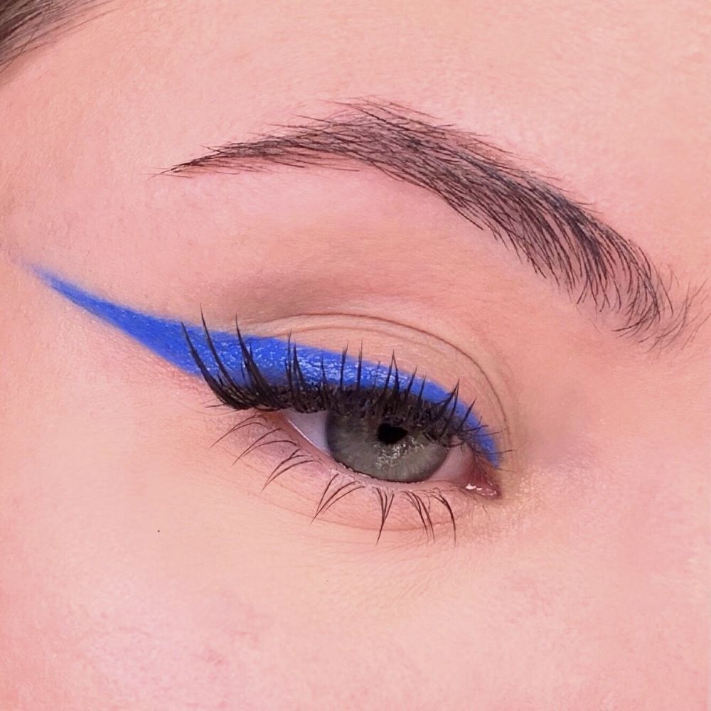 Occhio con eyeliner blu. Tratto di eyeliner blu sopra le ciglia superiori. Ciglia e sopracciglia visibili.