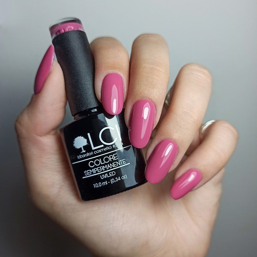 Mano con unghie smaltate e flacone di smalto. Colore rosa. Scritta: LCI, Colore Semipermanente, UV/LED.