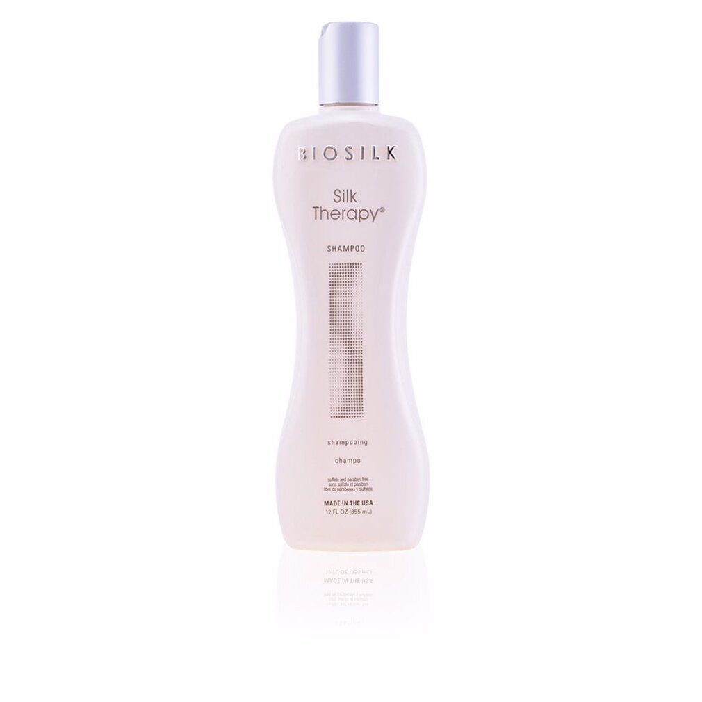 Flacone di shampoo Biosilk Silk Therapy. Design bianco sagomato, tappo argentato. Testo: Shampoo, Made in the USA.