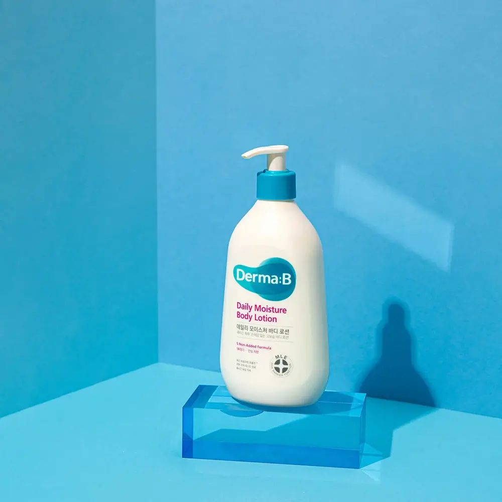 Flacone bianco con tappo e pompa blu su piedistallo blu. Scritta: Derma:B Daily Moisture Body Lotion.