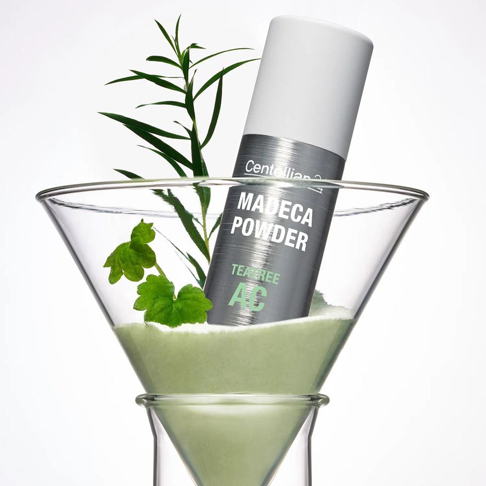 Flacone Centellian24 Madeca Powder TeaTree AC in un bicchiere con polvere e piante.