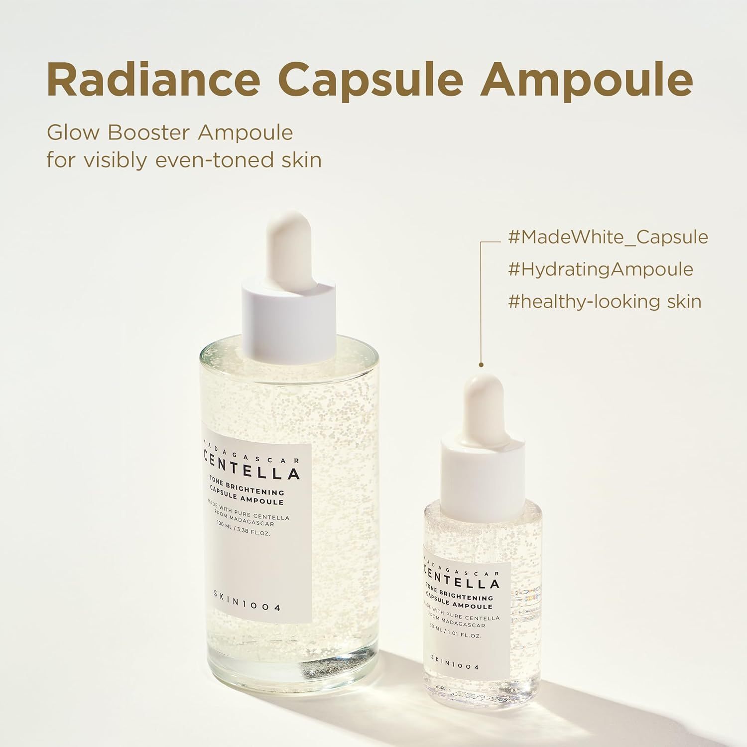 Due fiale con contagocce, una grande e una piccola. Testo: Tone Brightening Capsule Ampoule. SKIN1004. Sfondo: chiaro.