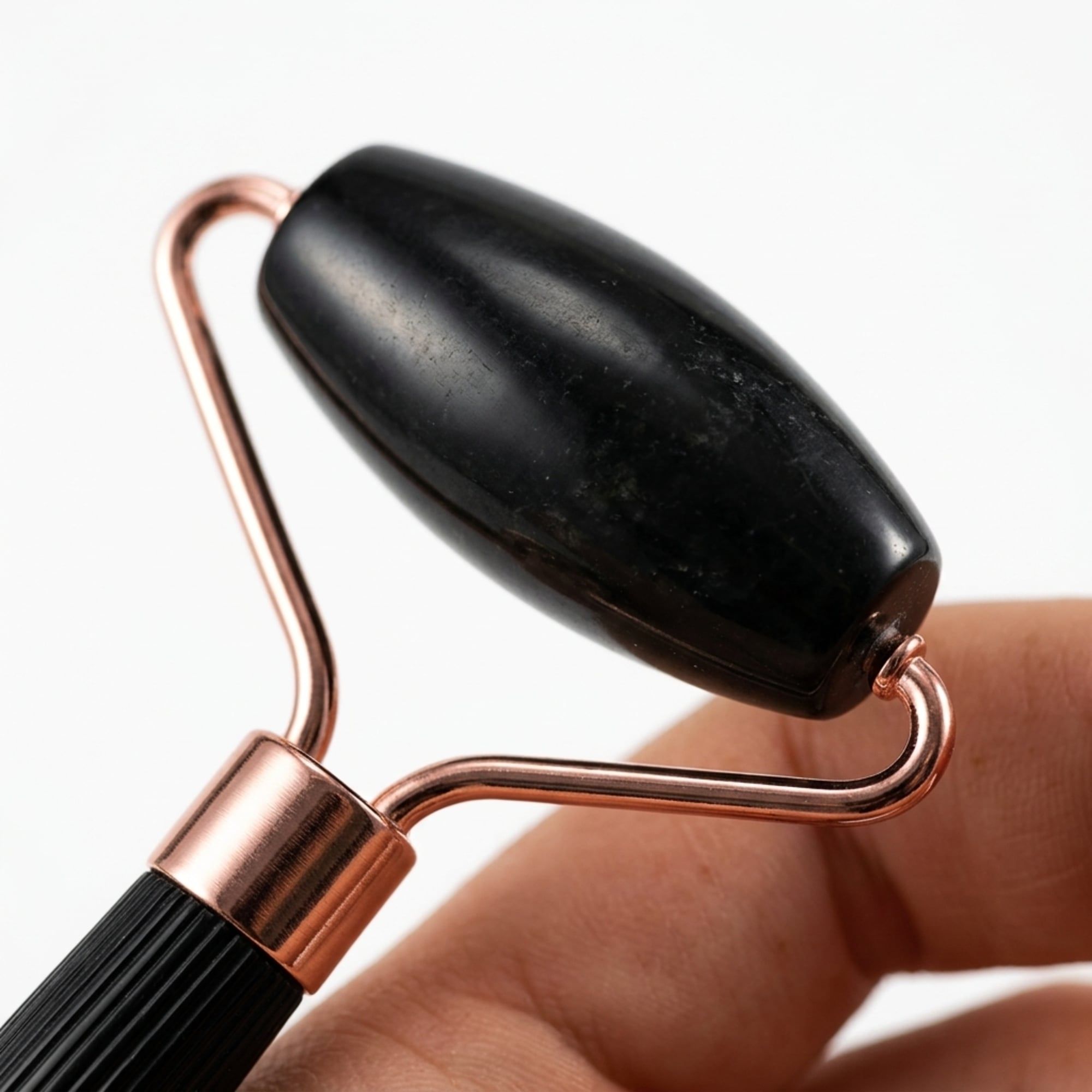 Rullo di giada nero con telaio metallico color rame, tenuto da una mano.