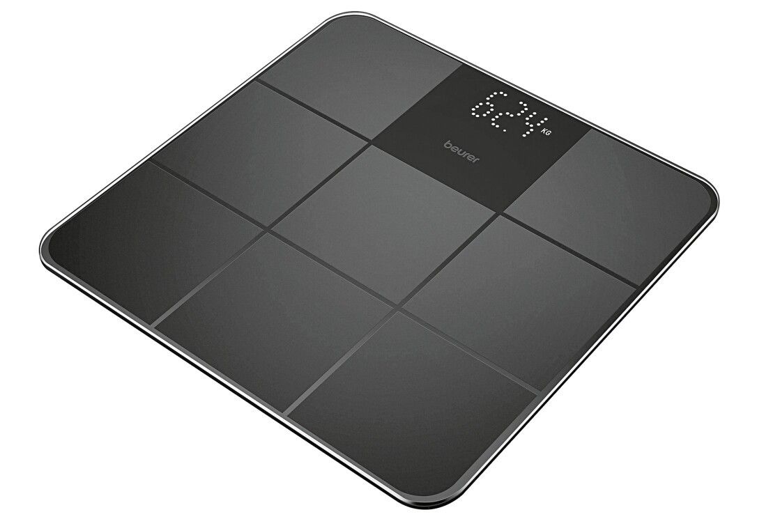 Bilancia digitale nera. Marchio Beurer. Mostra 62,4 kg. Forma quadrata con nove sezioni. Superficie in vetro.