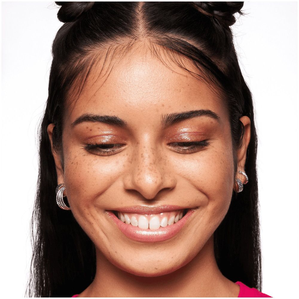 Primo piano di un viso sorridente. La pelle è liscia e uniforme. Occhi chiusi.