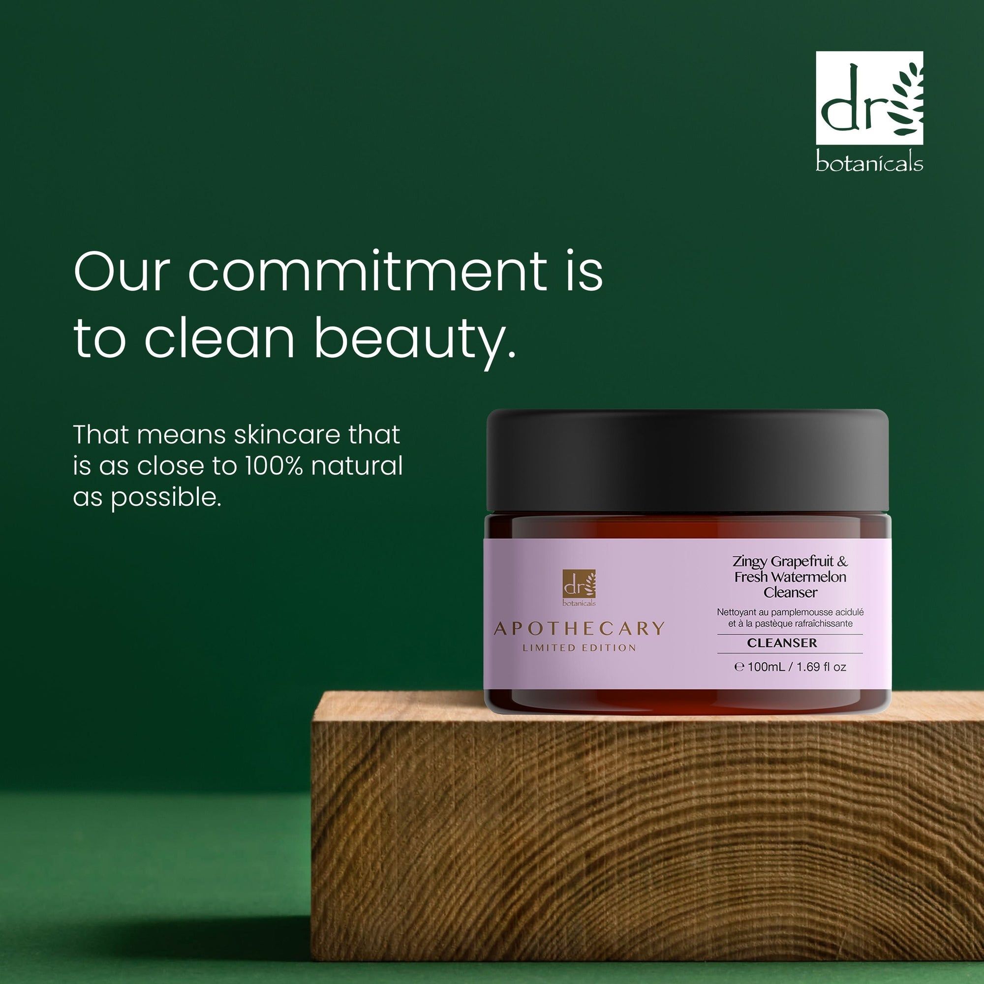 Vaso marrone con coperchio nero. Etichetta con nome del prodotto e marchio. Testo: Our commitment is to clean beauty. Su blocco di legno.
