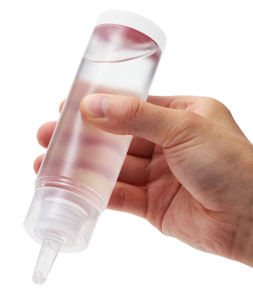 Mano che tiene un flacone di Tenga Lotion Mild dal contenuto trasparente.