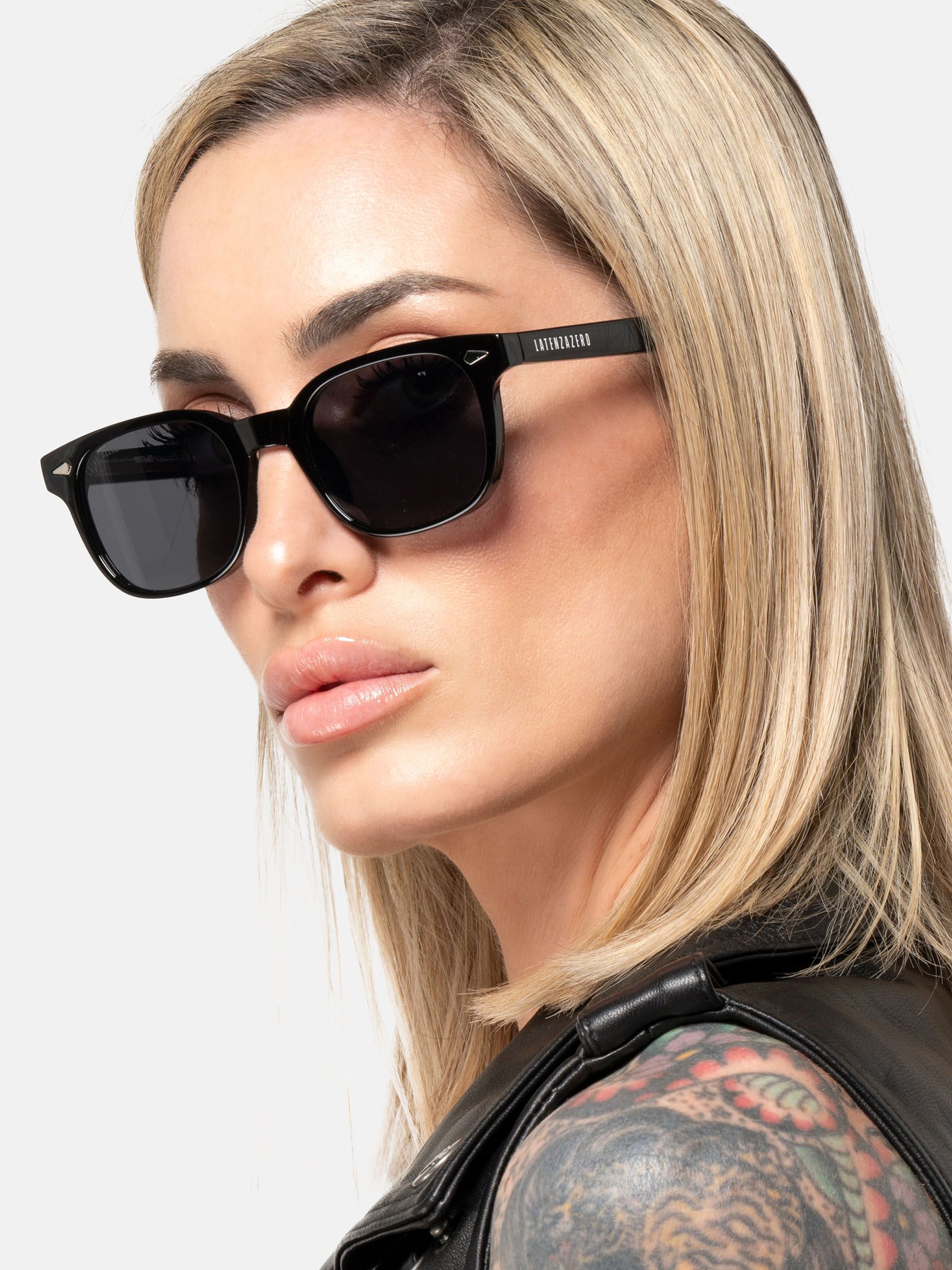 Donna con occhiali da sole neri. Logo Latenzazero sull'asta.