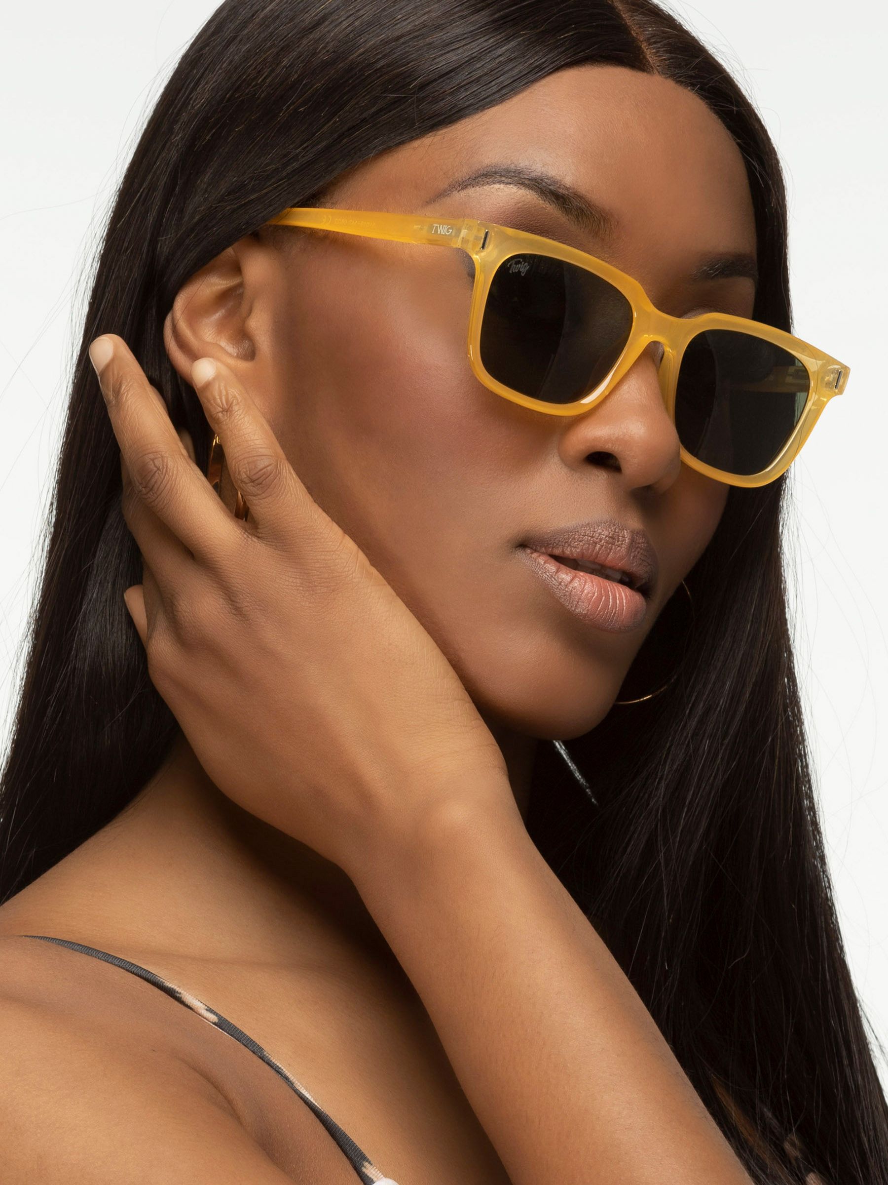 Donna con occhiali da sole gialli. Forma rettangolare, lenti scure. Primo piano.
