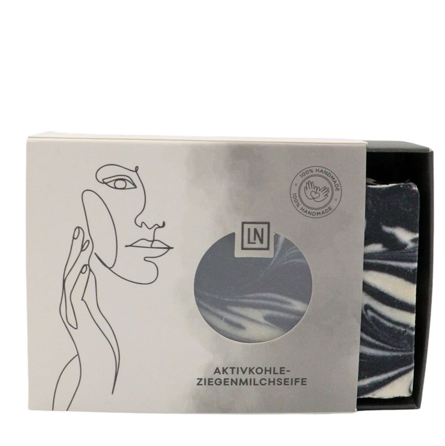 Scatola con sapone. Sapone nero con vortici bianchi. Sulla scatola c'è scritto Aktivkohle-Ziegenmilchseife.