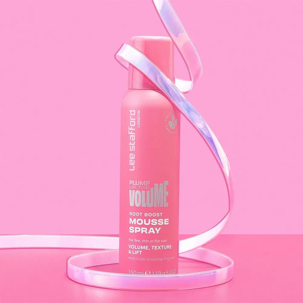 Flacone spray rosa con nome e logo del prodotto. Nastro decorativo avvolge il flacone. Sfondo rosa.