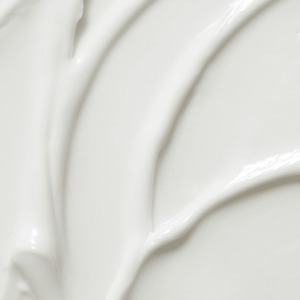 Primo piano di crema bianca. Texture liscia con linee ondulate.