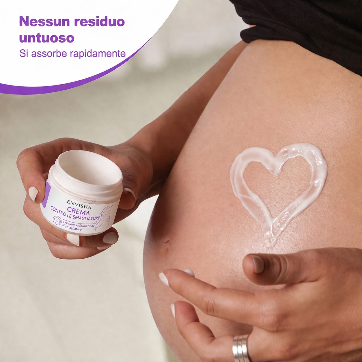 Vasetto di crema ENVISHA applicato sulla pancia. Testo: Nessun residuo untuoso, assorbimento rapido.