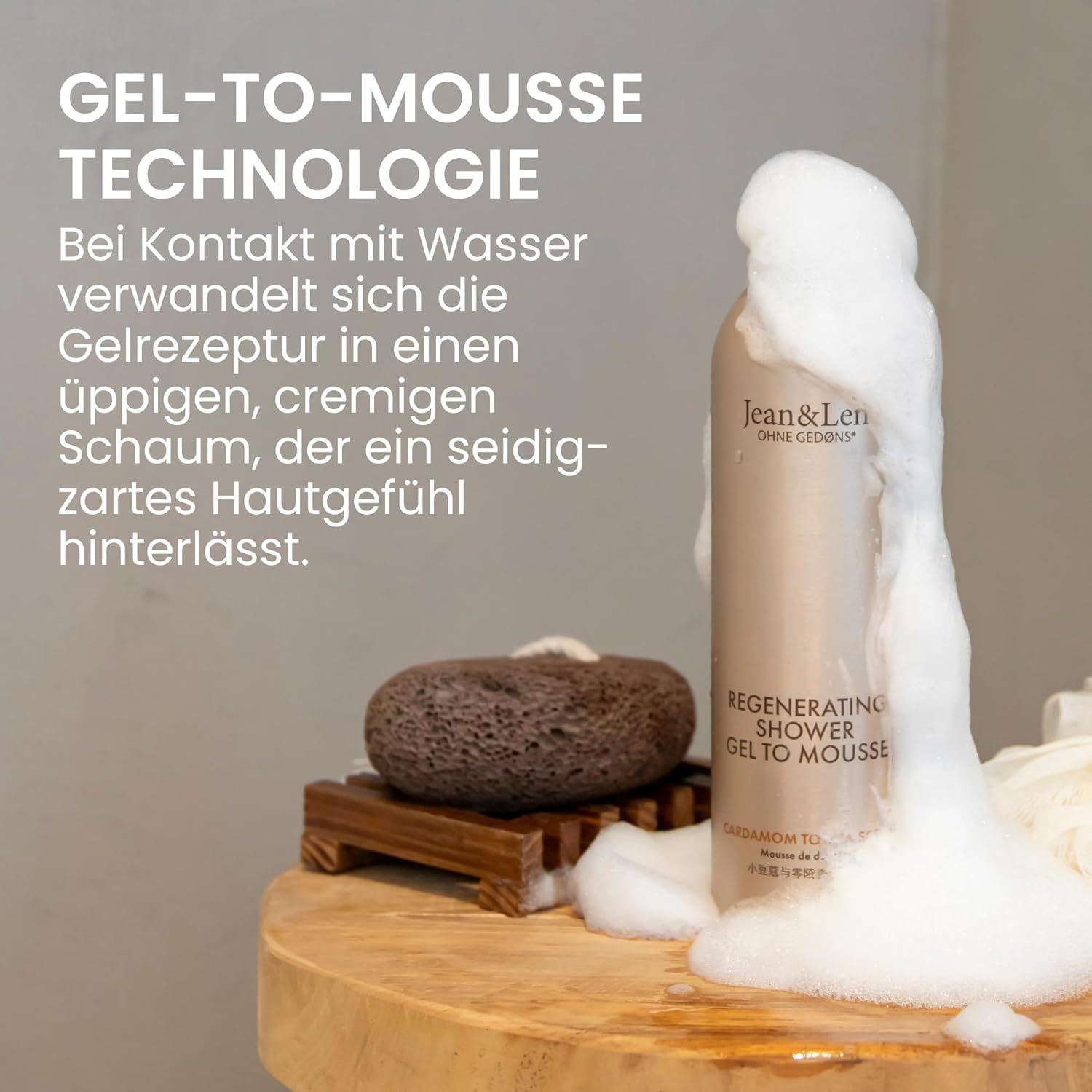 Flacone beige con tappo bianco. Schiuma che fuoriesce. Testo: Jean & Len, Regenerating Shower Gel To Mousse.