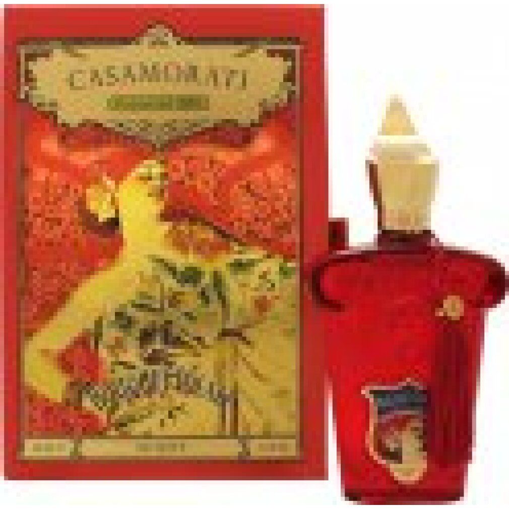 Flacone rosso con tappo dorato e nappa, accanto a confezione rossa con grafica e scritta.