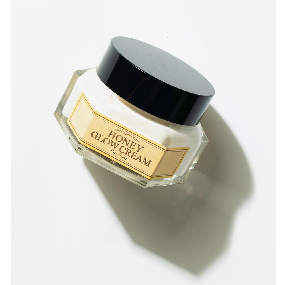 Vasetto di crema con coperchio nero. Scritta: HONEY GLOW CREAM, I'm from. Etichetta gialla. Vista obliqua.