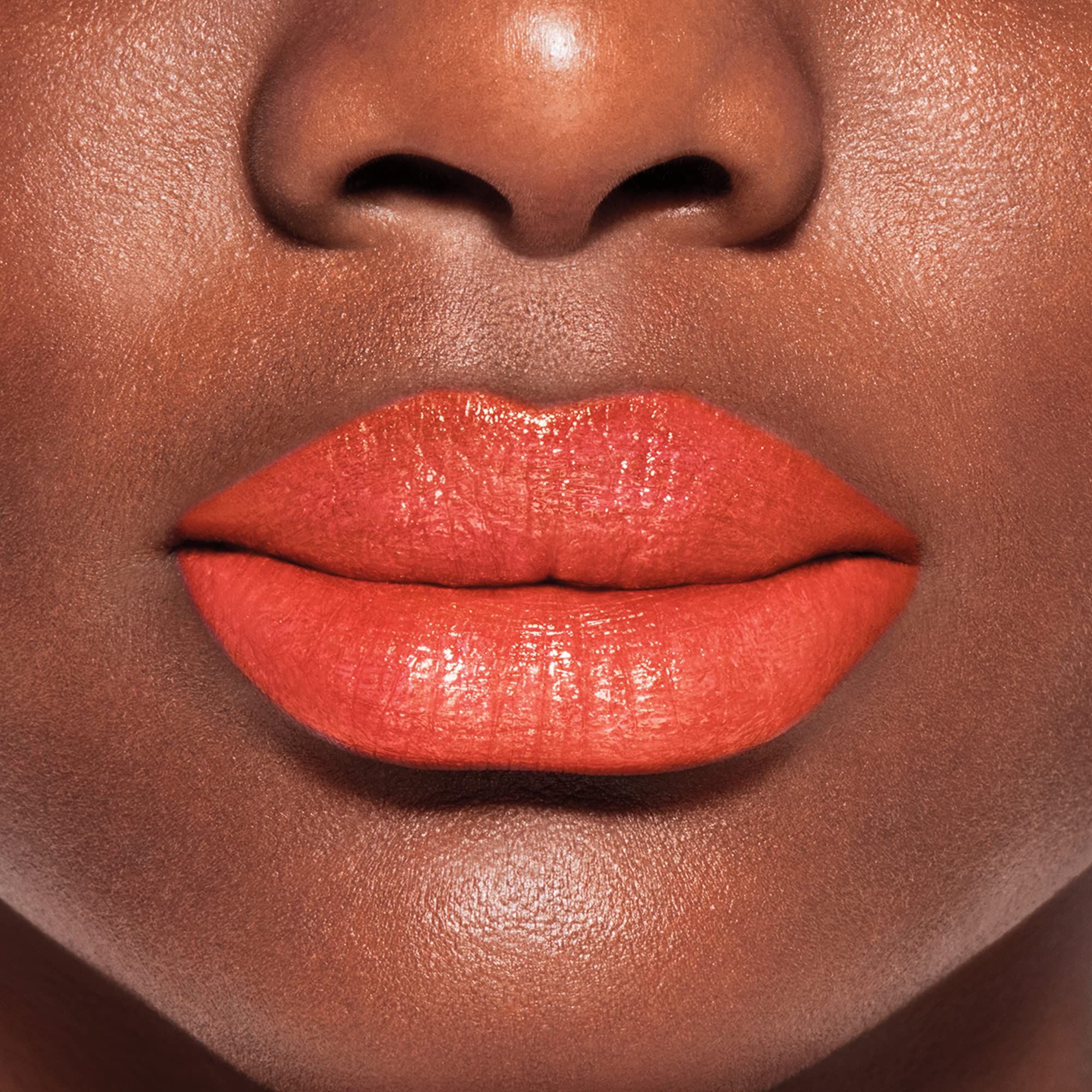 Primo piano di labbra con balsamo labbra arancione. Carnagione scura.