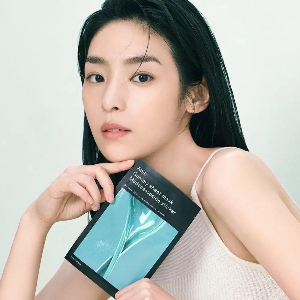 Una donna tiene l'Abib Gummy Sheet Mask Madecassoside Sticker davanti a sé.