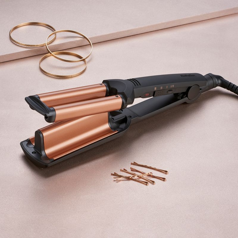 Ferro arricciacapelli Babyliss. Corpo nero, piastre ondulate color rame. Forcine e braccialetti dorati.
