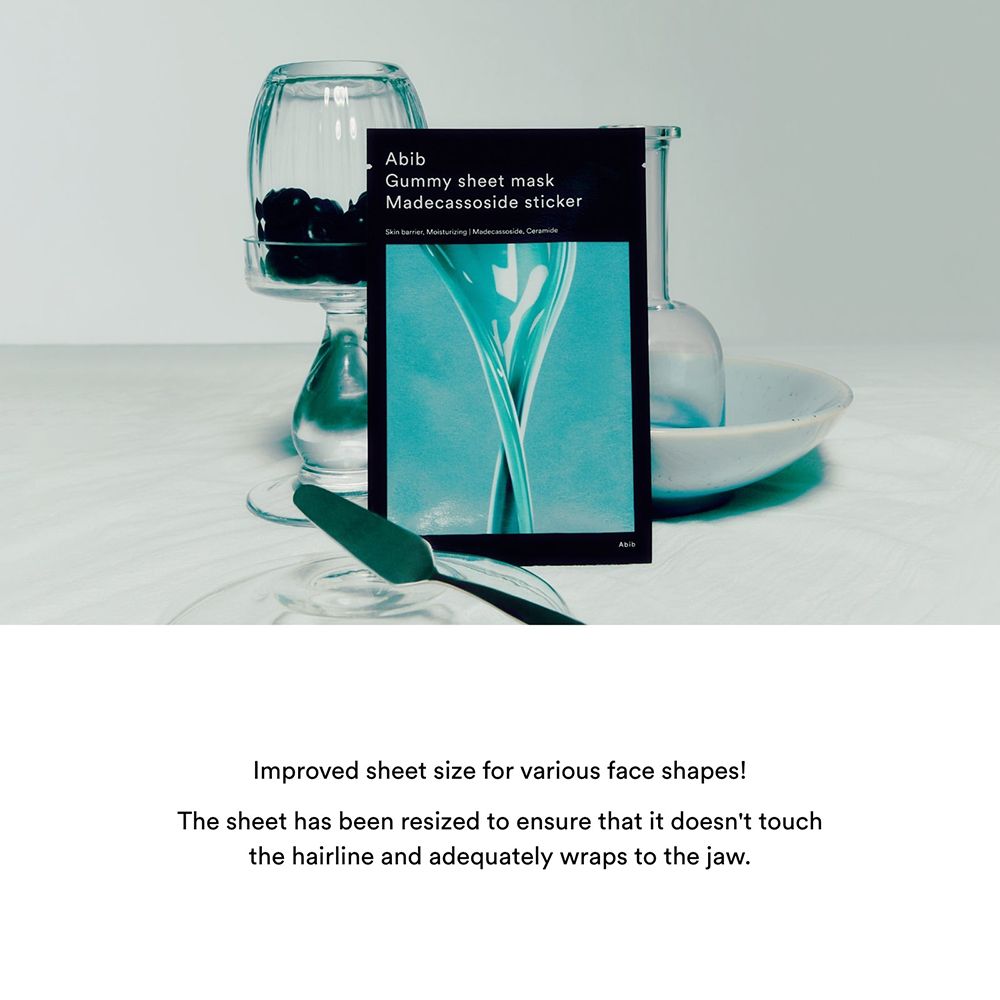 Confezione del prodotto accanto a oggetti di vetro. Confezione nera con nome e ingredienti del prodotto.