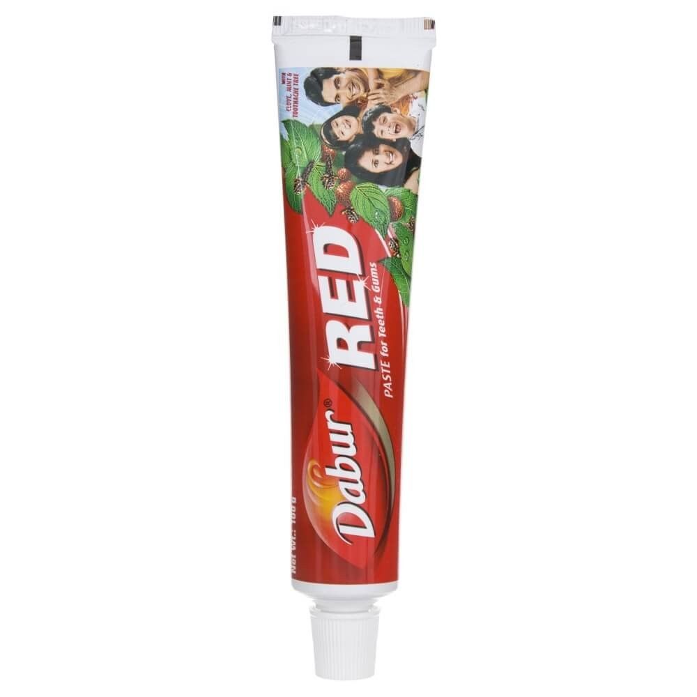 Tubo di dentifricio Dabur Red con design rosso e immagine di famiglia sul davanti.