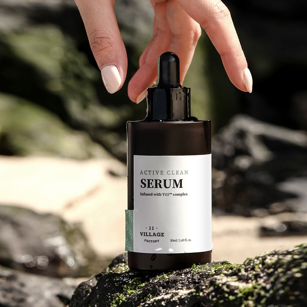 Flacone di siero marrone con tappo nero e contagocce. Etichetta con nome del prodotto e logo. Mano che tocca il flacone.