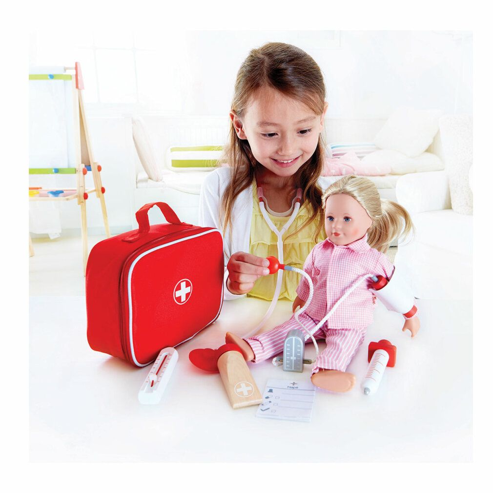 Bambina gioca con Hape Dein Doktorset: siringa, stetoscopio, bambola e borsa medica.