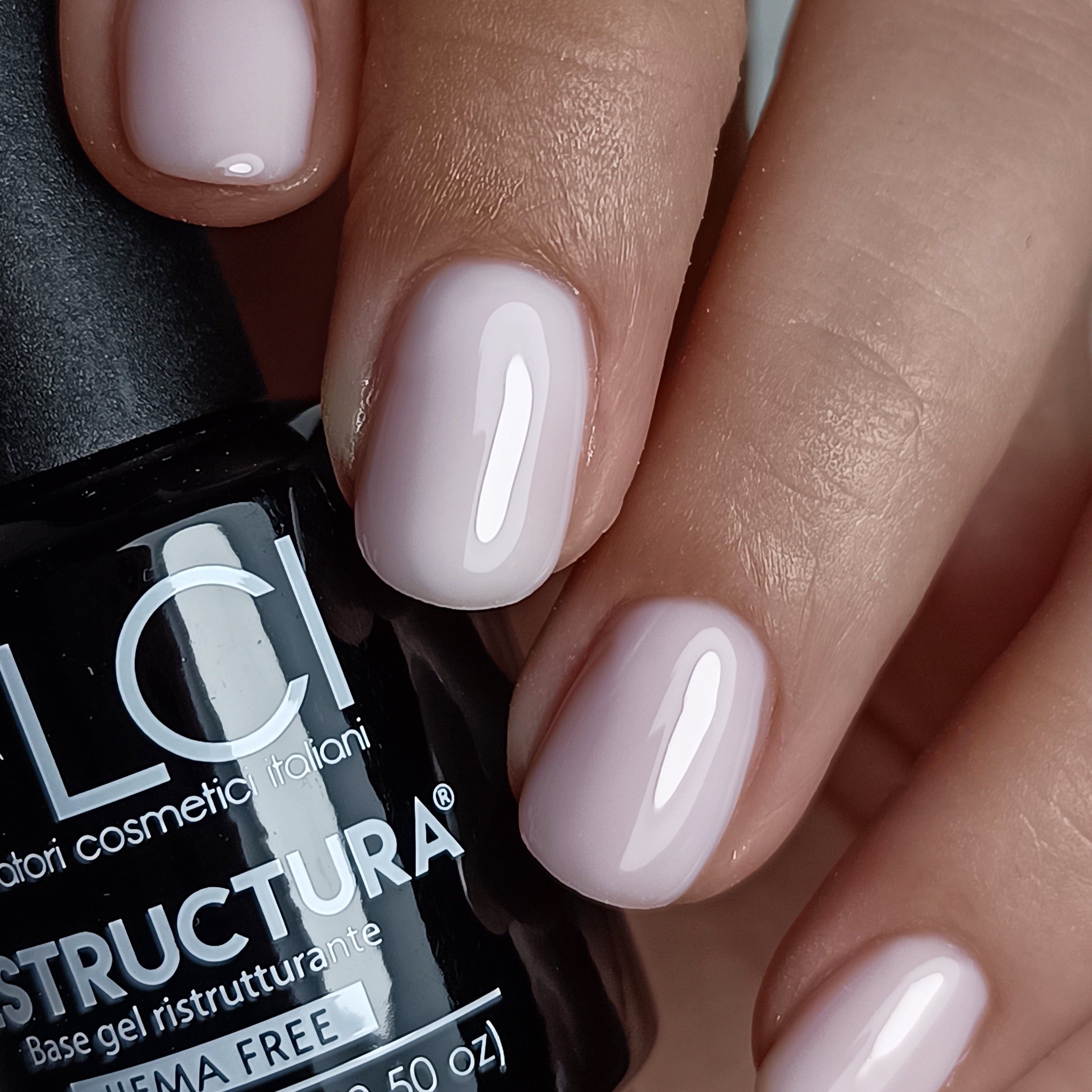 Unghie con smalto gel lilla chiaro. Flacone con scritta: LCI, Restructura, HEMA FREE.