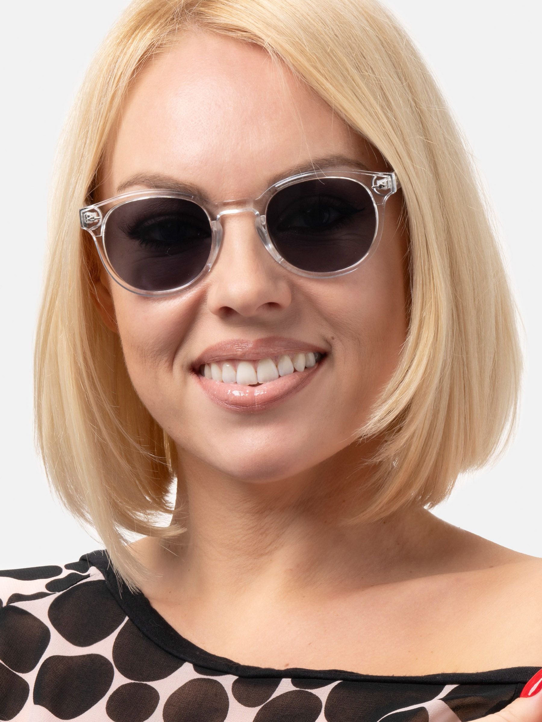 Donna bionda con occhiali da sole rotondi, montatura trasparente, lenti scure.