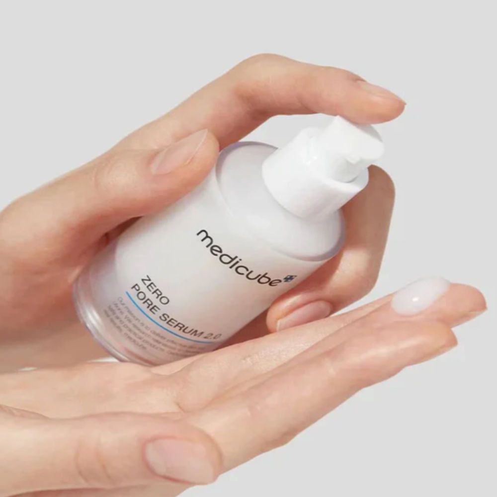 Mani che tengono un flacone di siero. Il siero viene applicato sul palmo. Scritta: medicube, ZERO PORE SERUM 2.0.