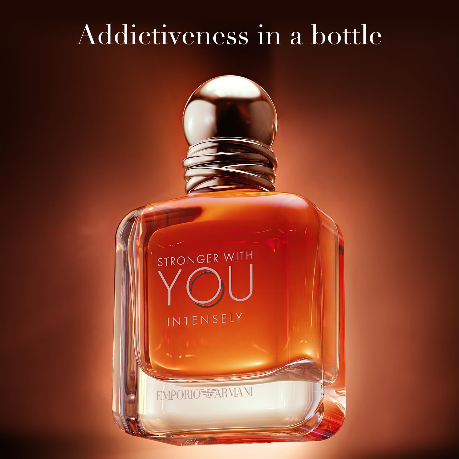 Flacone in vetro con liquido arancione. Tappo nero. Scritta: Stronger With You Intensely, Emporio Armani. Testo: Addictiveness in a bottle.
