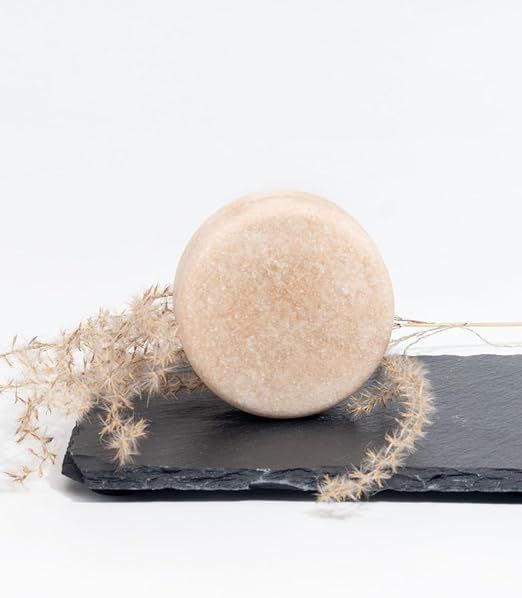 R5 Docciaschiuma Solido, rotondo, su ardesia nera. Decorazione con piante secche. Sfondo bianco.