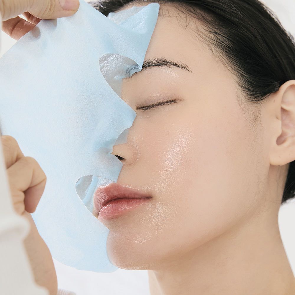 Primo piano di un viso con una maschera facciale in applicazione. La maschera è blu e copre la pelle.