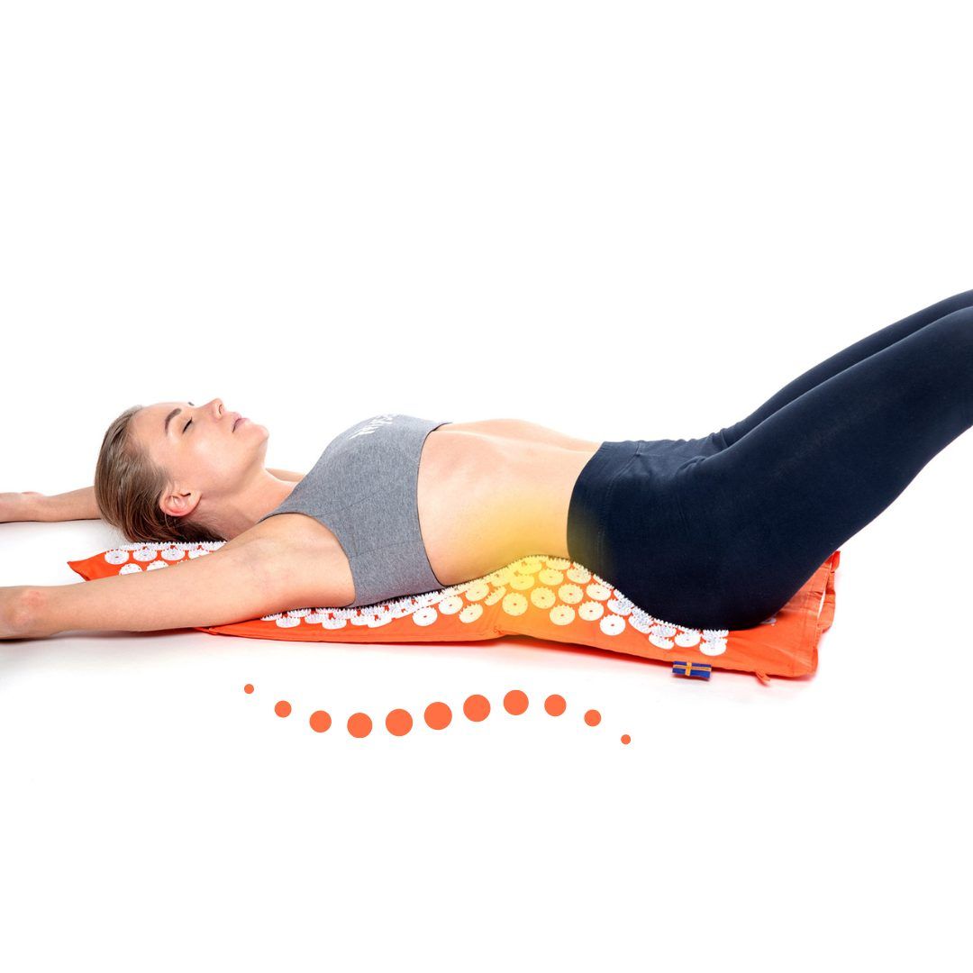 Donna sdraiata su un cuscino arancione con punte bianche. È sdraiata sulla schiena.