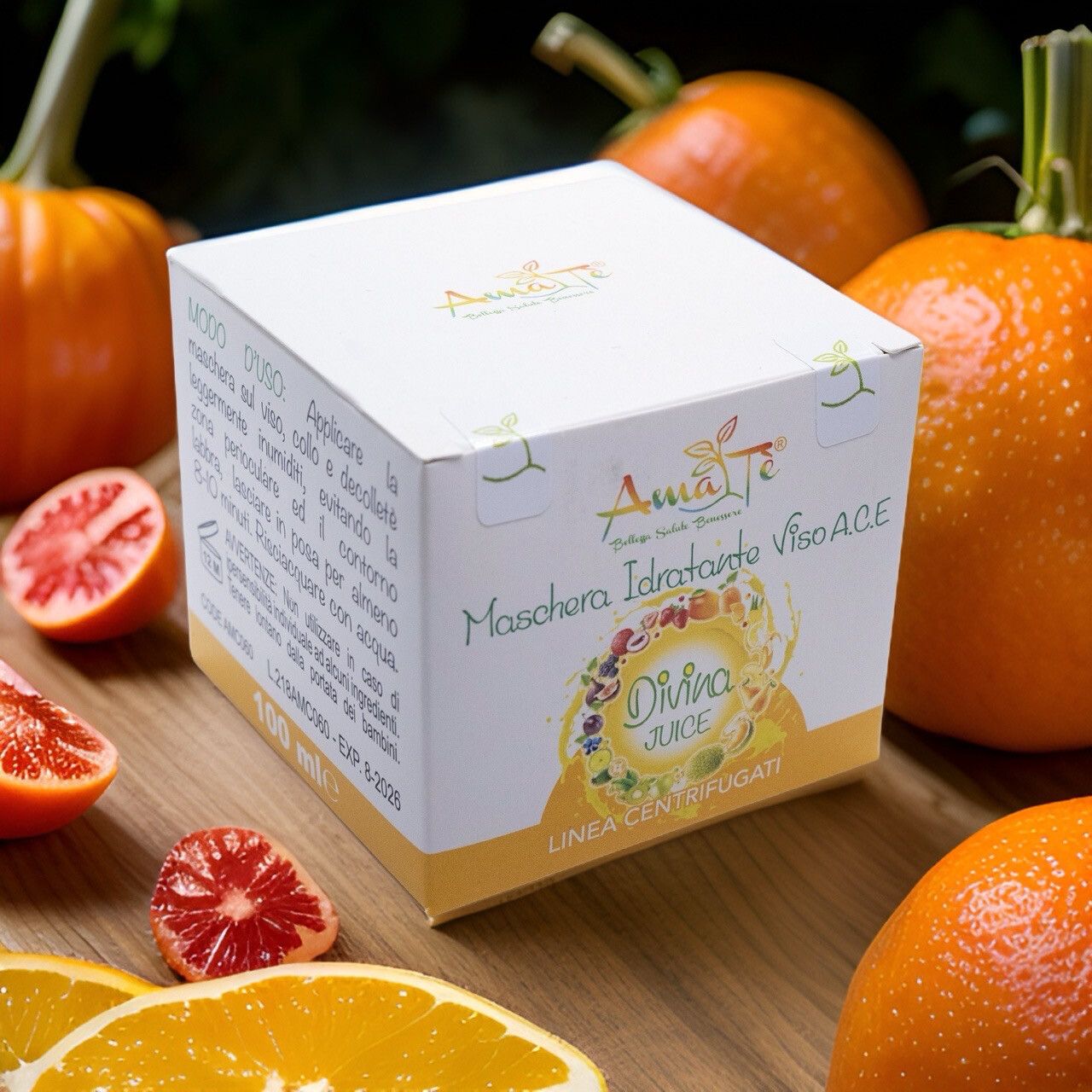 Confezione prodotto su fondo legno con arance e arance rosse. Scritta: Maschera Idratante Viso A.C.E. Divina Juice. Logo Amatè.