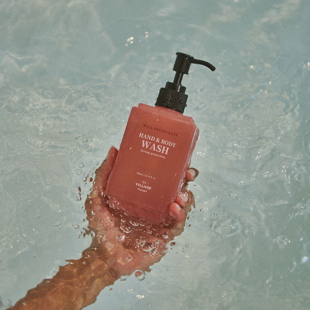 Flacone di detergente mani e corpo. Contenitore rosa con erogatore nero. Testo: Hand & Body Wash, Strong Protection.