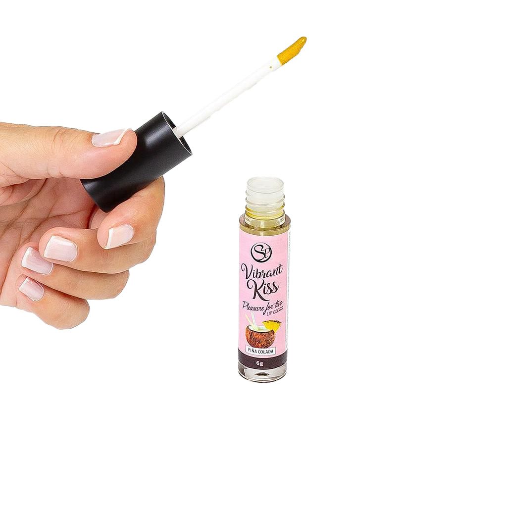 Lucidalabbra trasparente in un piccolo flacone. Un applicatore è tenuto in mano. Scritta: Vibrant Kiss, Pina Colada.
