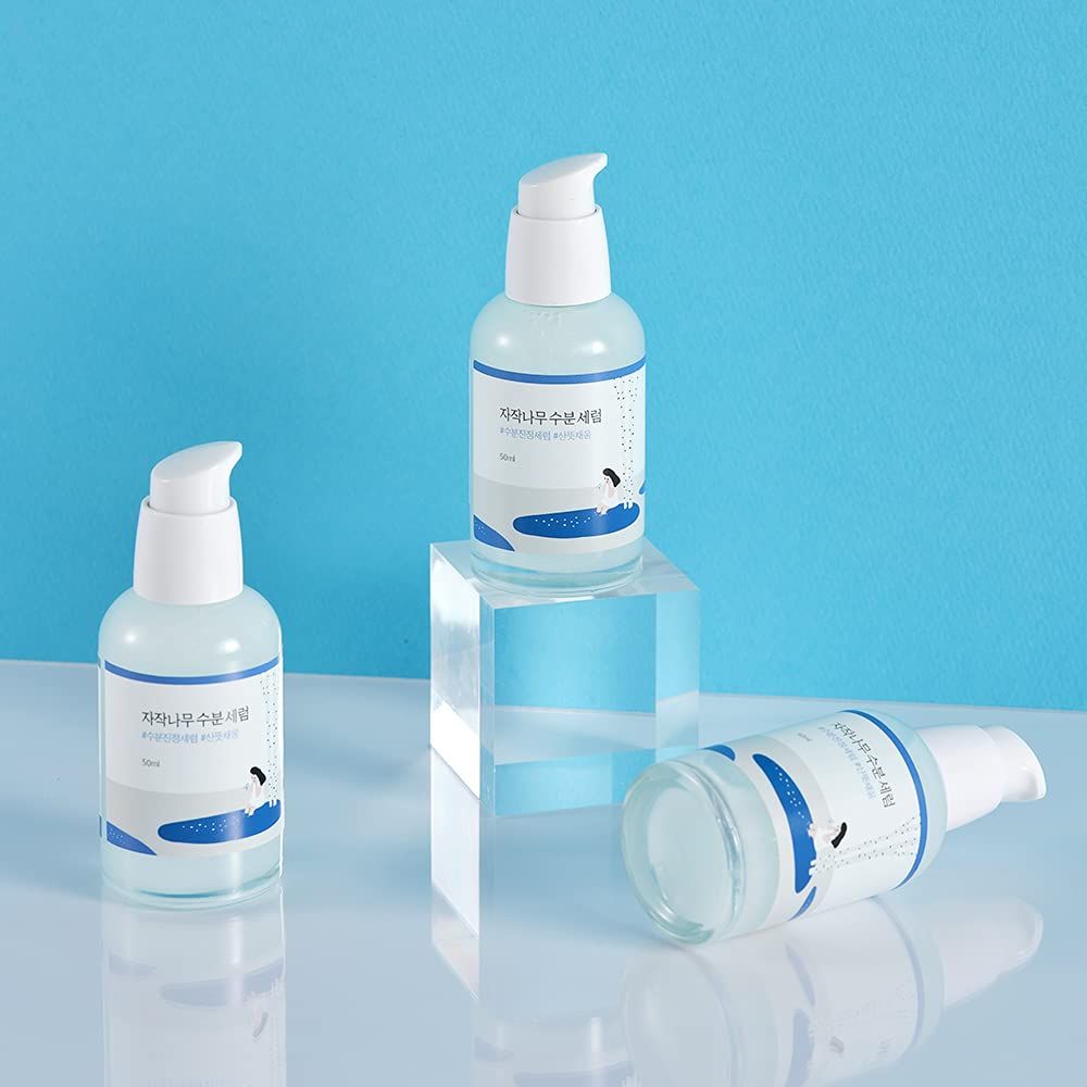 Tre flaconi con dosatore bianco. Etichette con caratteri. Uno in piedi, uno sdraiato, uno su un piedistallo.